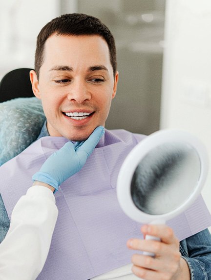 Man smiling at reflection in mirror with dentist