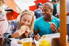 Friends smiling while enjoying meal outside