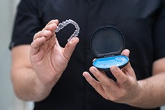 Patient putting clear aligners in storage case