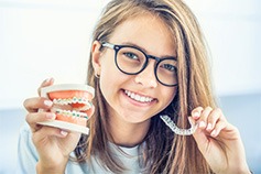 a teen holding braces and clear aligners