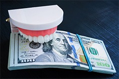 a model of a mouth biting down on a stack of cash