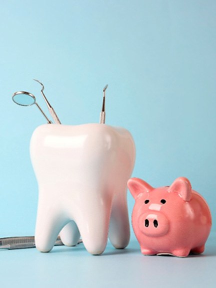 Dental tools in tooth-shaped holder next to piggy bank