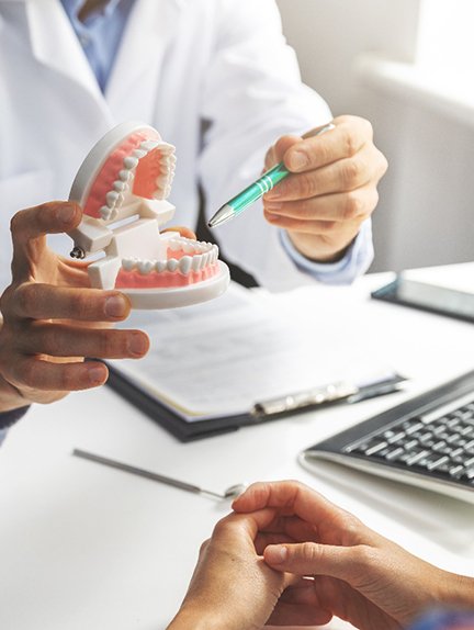 Dentist showing patient model of teeth